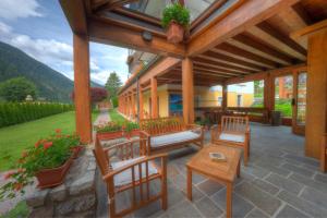 a covered patio with chairs and a table at Hotel Panoramic in Auronzo di Cadore