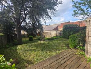 a yard with a wooden deck and a tree at Côté Jardin in Bolbec