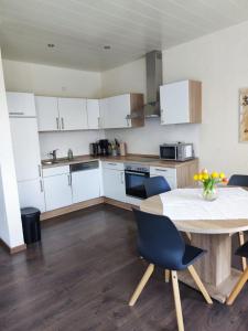 a kitchen with white cabinets and a table with chairs at Landferien Eifel in Pittenbach