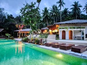 a swimming pool in front of a house at Arcana Wellness Center - Adults Only in Ko Phangan