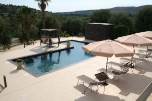 a swimming pool with chairs and umbrellas and a pool at Villa Badessa in Noto