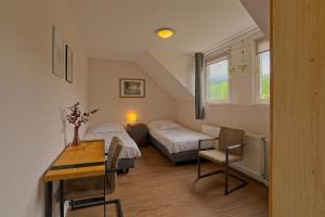 a bedroom with two beds and a table and a desk at Panzió-Kemping Bekölce in Bekölce