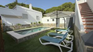 a swimming pool with two chairs and an umbrella at Casa La Herradura 1 in Vejer de la Frontera