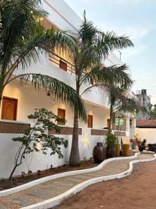 a white building with palm trees in front of it at Dreamy serenity beach side in Pondicherry