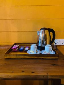 a tea kettle and two cups on a wooden table at Walawa Wild Place in Udawalawe
