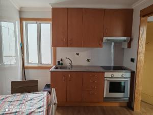 a kitchen with wooden cabinets and a sink and a stove at La Casita de la Suerte 3ro in Marín