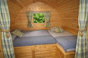 two beds in a log cabin with a window at Glamping Cabins in the Heart of Snowdonia in Dolgellau