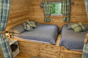 two beds in a log cabin with a window at Glamping Cabins in the Heart of Snowdonia in Dolgellau