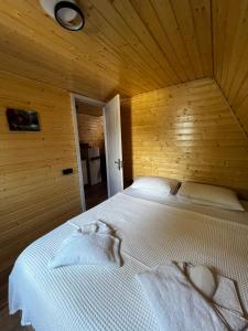 a bedroom with a large white bed in a wooden wall at Sweet Cottage in Kobuleti