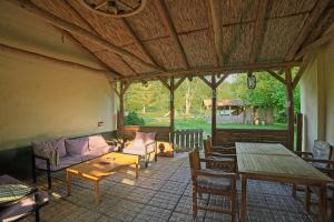 a screened in porch with a couch and tables at Panzió-Kemping Bekölce in Bekölce