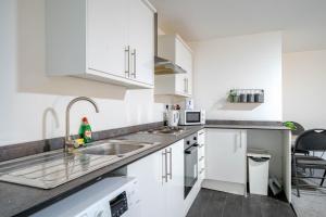 a kitchen with white cabinets and a sink at Studio Apartment Fully Equipeed with WiFi and Netflix in Ilkeston