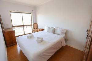 ein Schlafzimmer mit einem weißen Bett, auf dem zwei Handtücher liegen in der Unterkunft Amorosa Beach Rooftop - 400 metros da Praia in Viana do Castelo