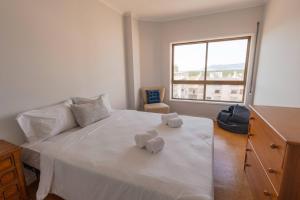 ein Schlafzimmer mit einem großen weißen Bett, auf dem Handtücher liegen in der Unterkunft Amorosa Beach Rooftop - 400 metros da Praia in Viana do Castelo