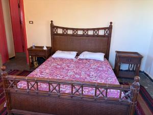 a bedroom with a large wooden bed with two tables at Al Obayed Garden Villa in Marsa Matruh