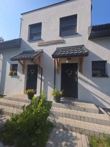 a white house with two doors and some stairs at W Olchach - lokal Klon in Wiktorowo