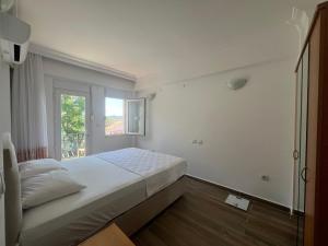 a white bedroom with a bed and a window at Heybe Apart in Kaş