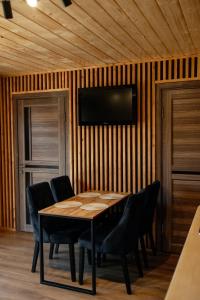 a dining room with a table and chairs and a television at House Riverside in Kozmacz