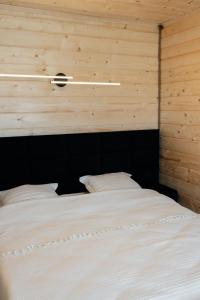 a white bed in a room with wooden walls at House Riverside in Kozmacz
