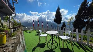 a table and chairs on a lawn with a fence at Baarish Home Stay in Kalimpong