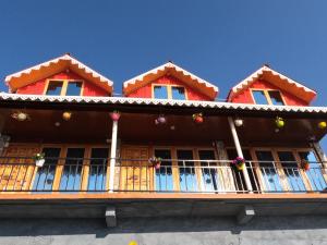 a red house with a balcony on top of it at Baarish Home Stay in Kalimpong