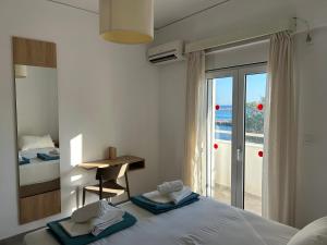 a bedroom with a bed and a desk and a window at Annoula Studios and Apartments in Kardamaina