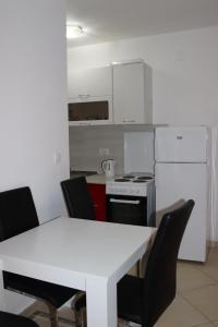 a kitchen with a white table and black chairs at Aurora Residence in Nalježići