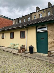 a yellow and green building with a green door at Step-free modern central apartment in Todmorden