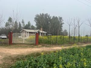 a small house in a field with a fence at RajKamal's Farm in Borās