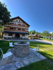 a building with chairs and a fire pit in the yard at Pensiunea Floare de Maramures in Vadu Izei