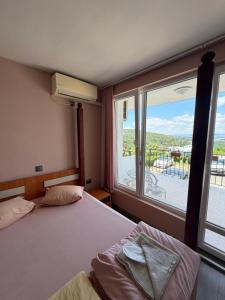 a bedroom with two beds and a large window at Family Hotel Ludo in Varna City