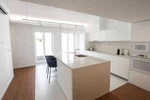a kitchen with white cabinets and a black chair at Décimus Lodge - Premium Town Center Stay in Ponte de Lima +55 photos