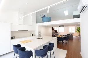 a kitchen with white cabinets and blue chairs at Décimus Lodge - Premium Town Center Stay in Ponte de Lima