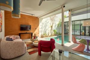 a living room with a tv and a swimming pool at Hotel Eden Ubud in Ubud