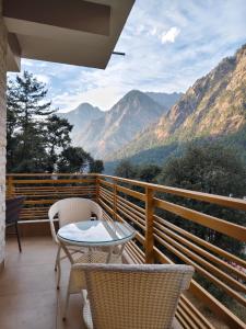 a balcony with a table and chairs and mountains at Himalayan Hideaway Homestay in Kasol