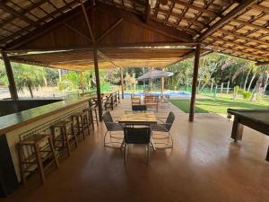 a patio with tables and chairs and an umbrella at Sítio Funilândia - MG in Funilândia