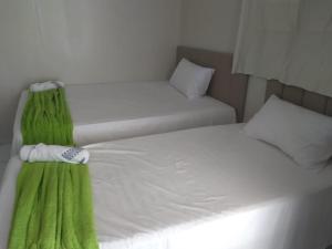 two beds with green sheets in a room at Hotel Paulista Sobradinho BA in Sobradinho - Bahia