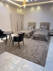 two beds in a room with a table and chairs at راحتي in Al Baha