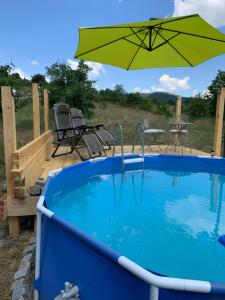 a pool with an umbrella and a table and chairs at The Cabin On the Hill in Belogradchik +21 photos