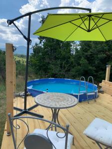 a table and chairs with an umbrella next to a pool at The Cabin On the Hill in Belogradchik
