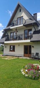 a large white house with a balcony and some flowers at Przy Potocku in Czarna Góra