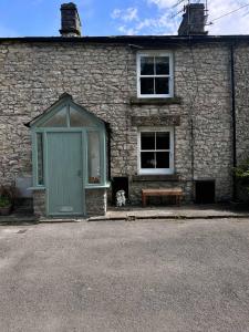 a dog sitting in front of a building with a bench at 2, The Lodge, Tideswell in Tideswell