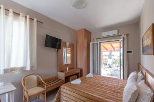 a bedroom with a bed and a tv and a window at Synodinos Studios in Lixouri