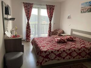 a bedroom with a bed and a chair and a window at Casa Poarta Paradisului in Moldoveneşti