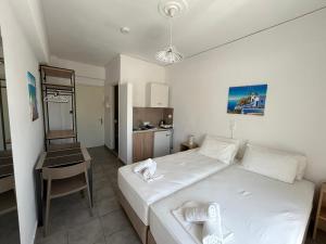 a bedroom with a white bed and a kitchen at Annoula Studios and Apartments in Kardamaina