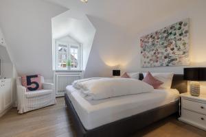 a bedroom with a large white bed and a chair at Strandliebe Sylt in Westerland