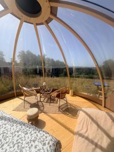 a room with a bed and chairs and a large window at La bulle de Clemence in Montfermy