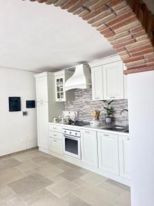 a white kitchen with white cabinets and a sink at Relax House Sardara in Sardara