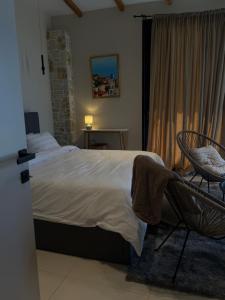 a bedroom with a bed and a chair and a window at Terracotta Villa in Himare