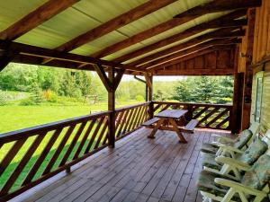 a wooden deck with a picnic table and chairs on it at Domek Samanta in Grzybina