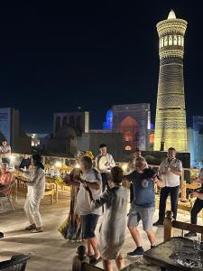 a group of people standing around a city at night at Golden Minaret with Terrace in Bukhara +65 photos